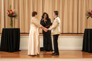 Toni James officiating as two people hold hands during a wedding ceremony
